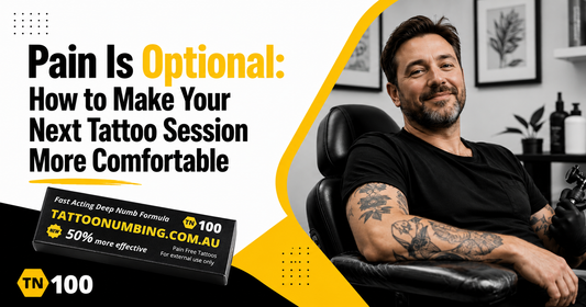 Pain Is Optional, relaxed client reclining in a tattoo studio chair beside TN100 tattoo numbing cream by Tattoo Numbing Australia